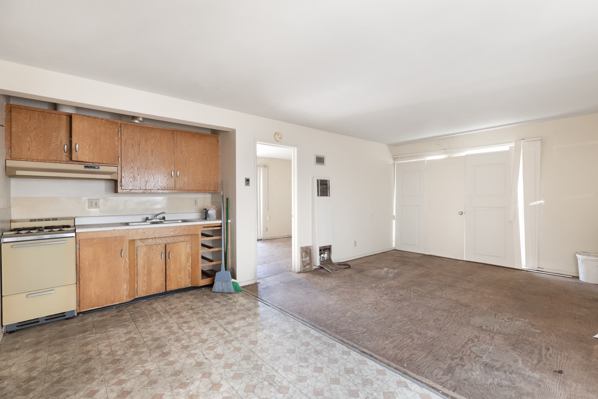 Before: Kitchen before renovation with dated cabinets and bare subfloor