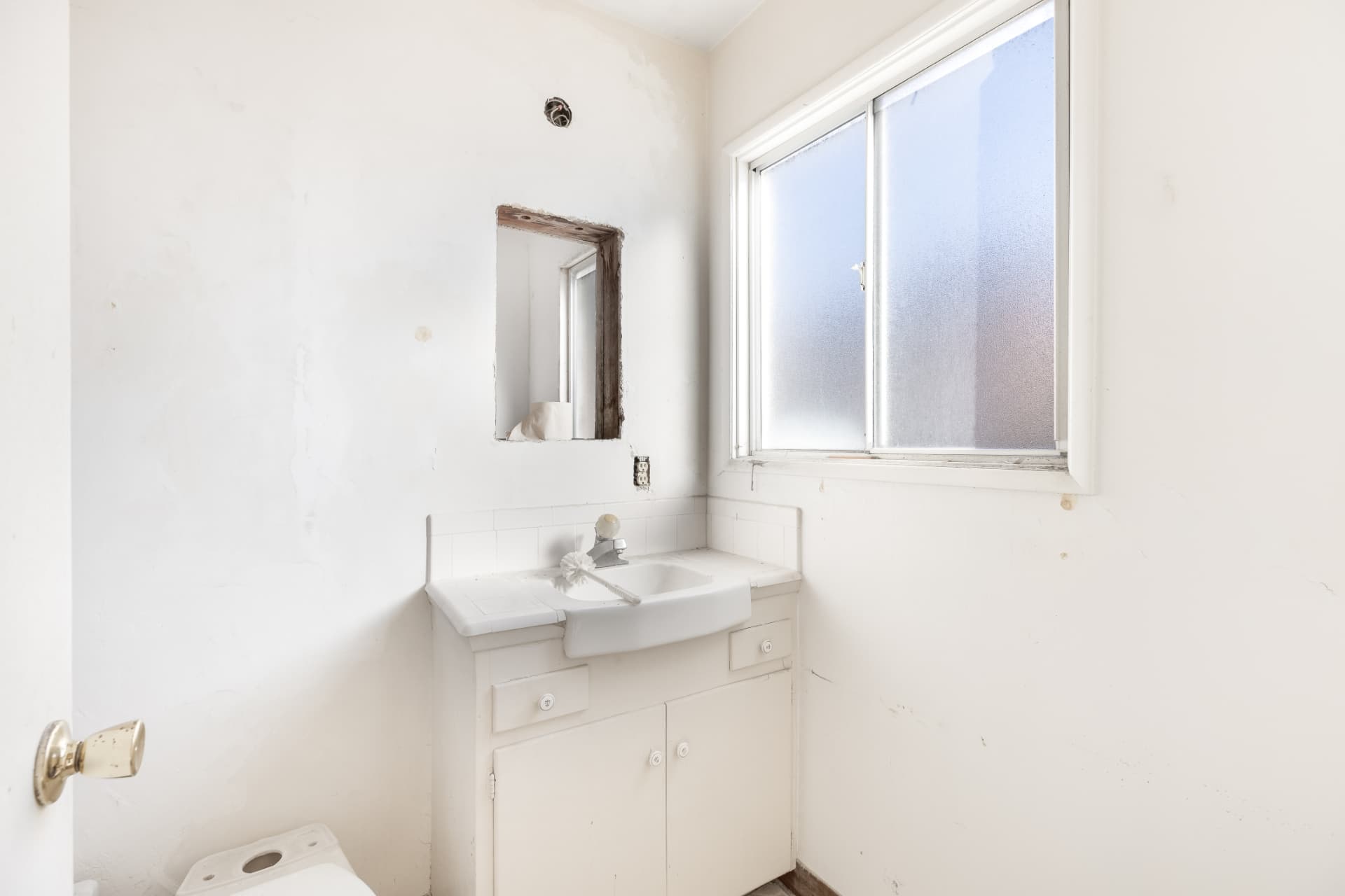 Before: Bathroom before renovation with unfinished wall opening and missing fixtures