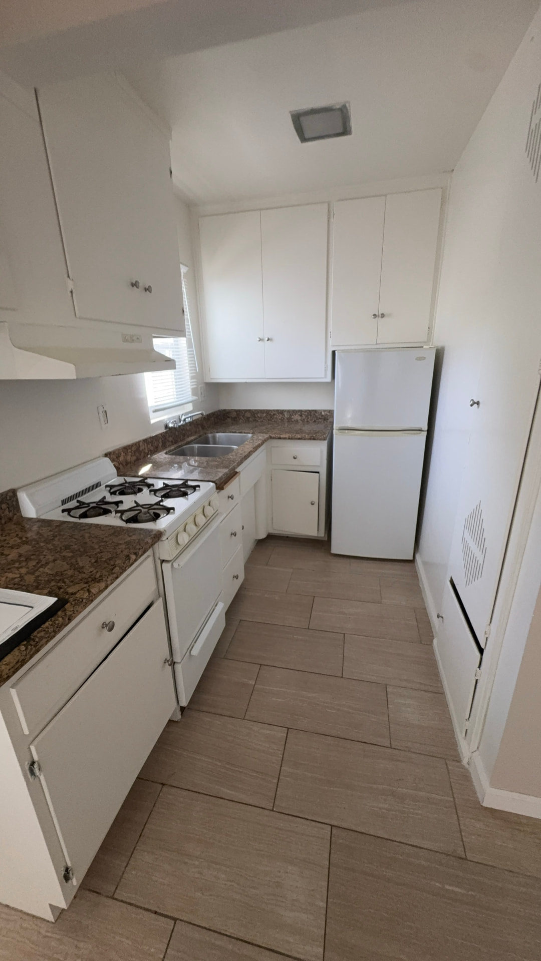 Before: Kitchen before renovation with dated flat-panel cabinets and old appliances