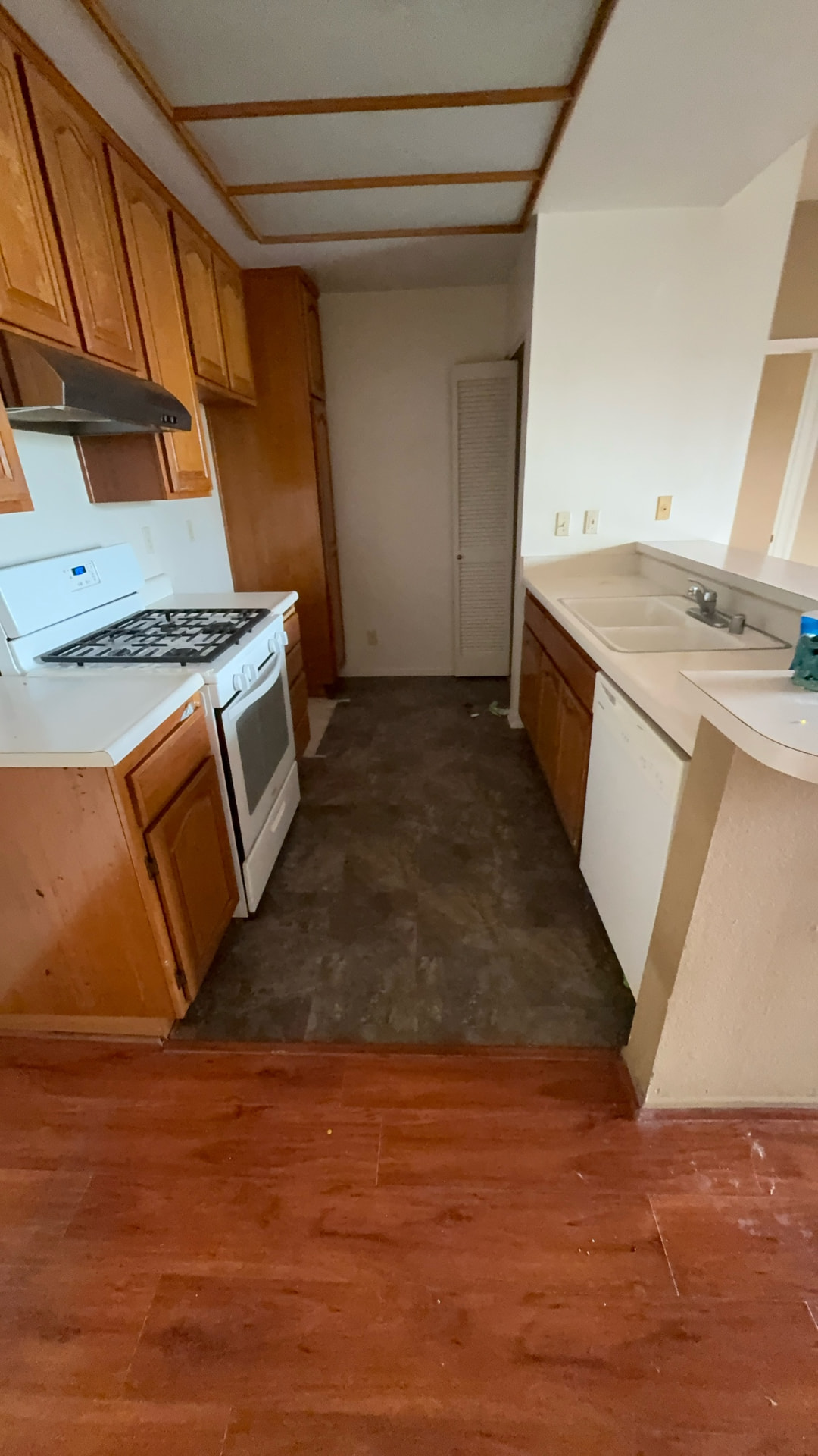 Before: Kitchen before renovation with dated wood cabinets and worn flooring