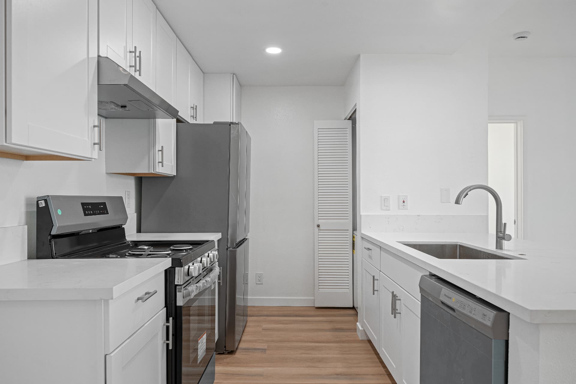 After: Renovated kitchen with white cabinetry, quartz countertops and stainless appliances