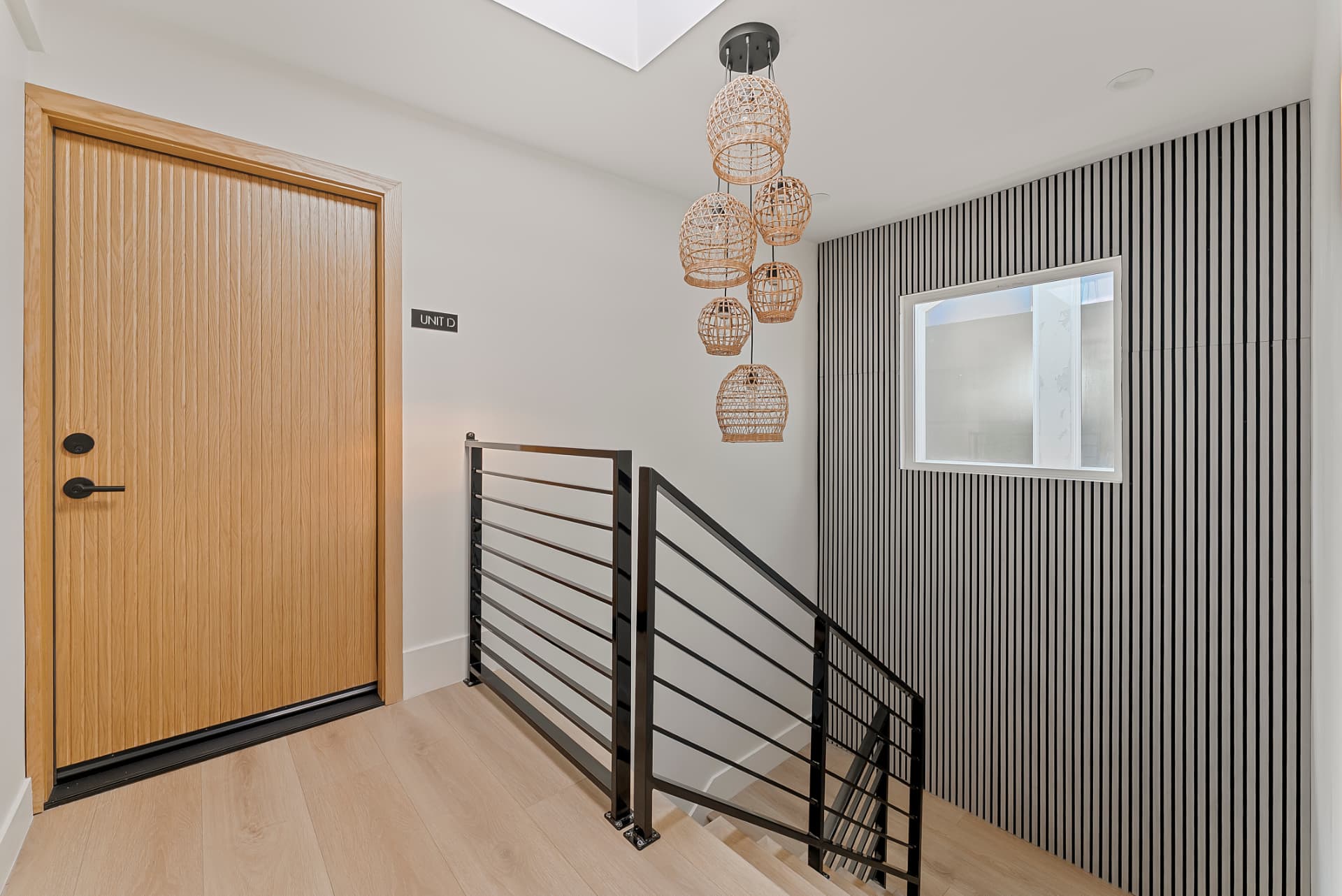 After: Renovated stairway landing with black metal railings, slatted feature wall and pendant lighting