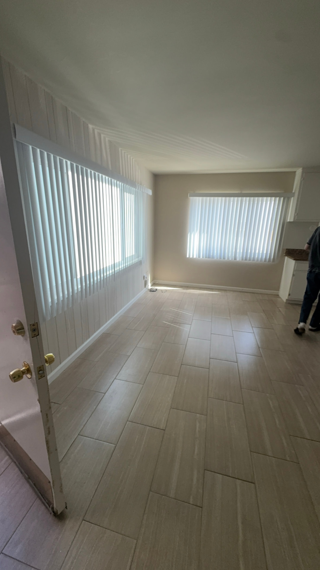 Before: Living room before renovation with vertical blinds and tile flooring