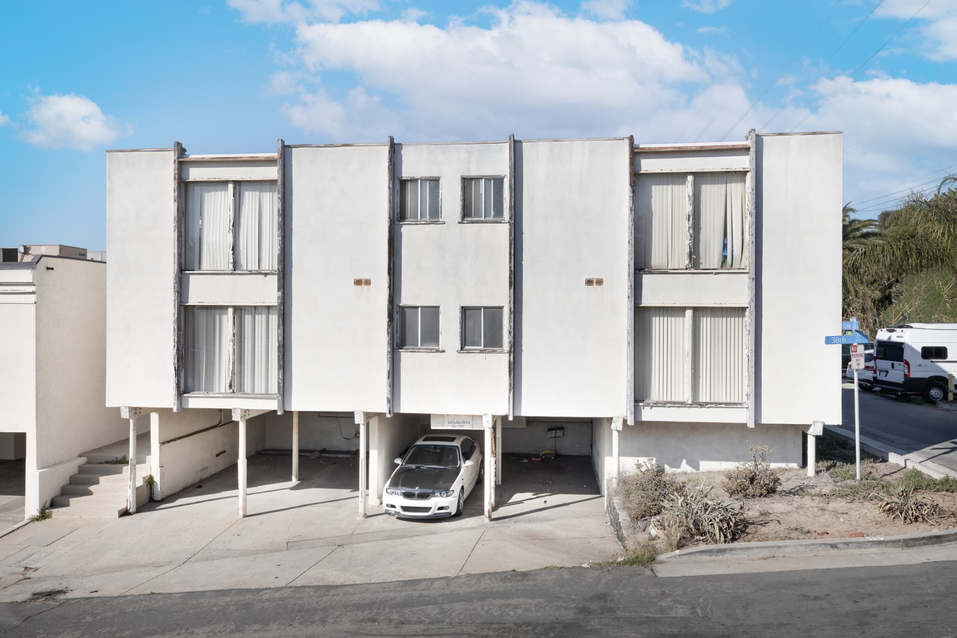 Before: Front of the Crest Dr building before renovation with weathered paint and dry landscaping