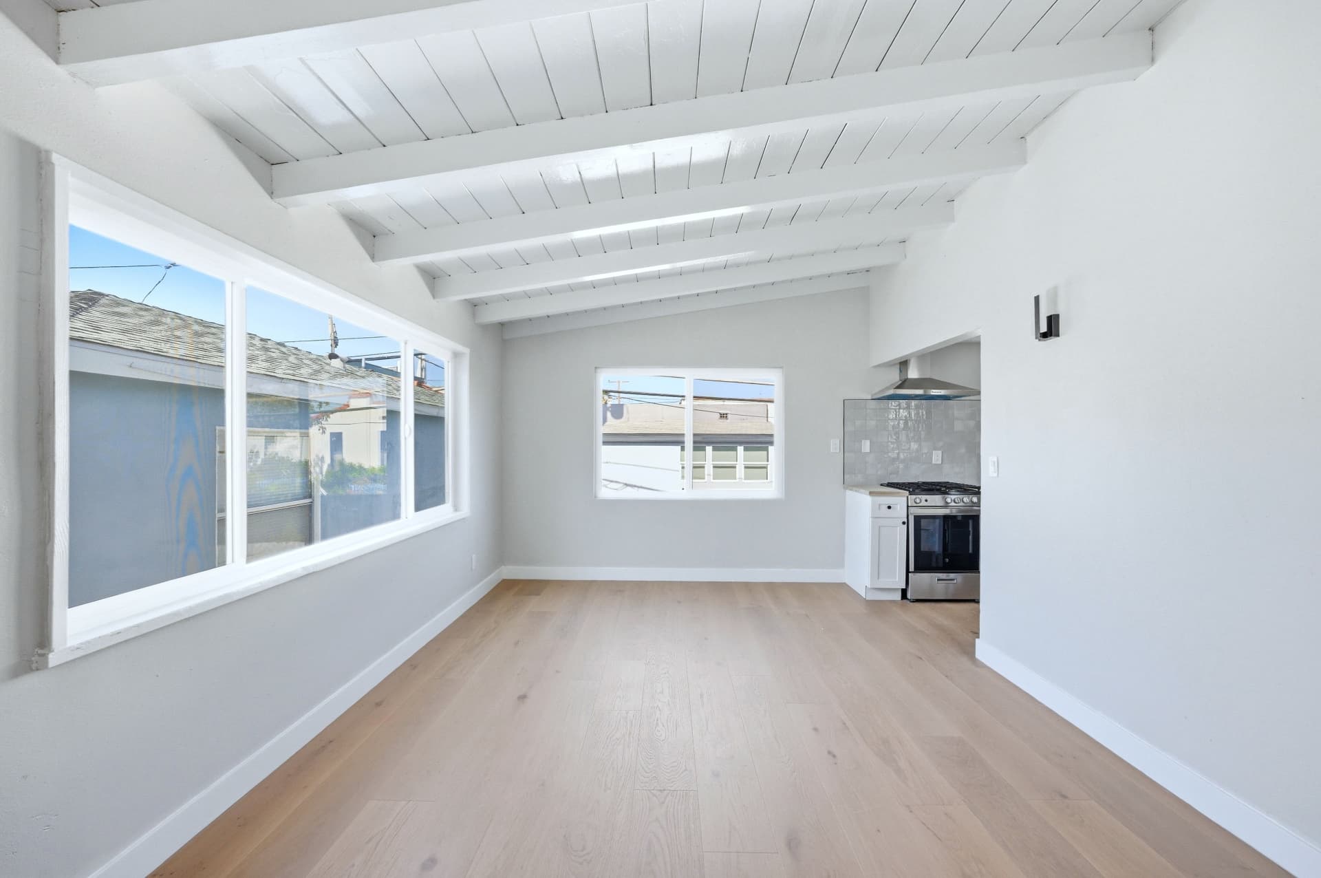 After: Renovated living area with beamed ceiling, new windows, luxury vinyl flooring and fresh paint