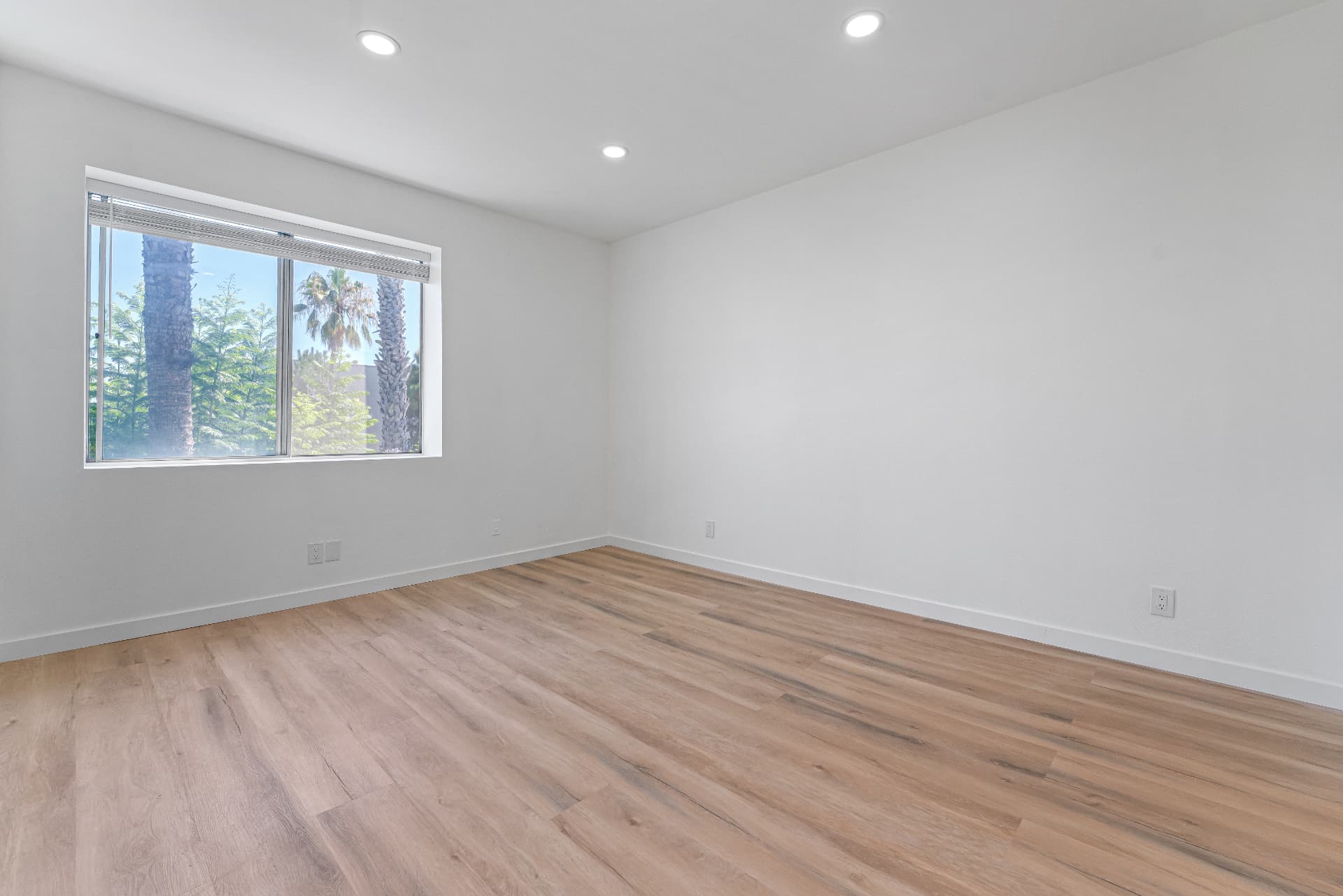 After: Renovated bedroom with fresh white paint, new wood-look flooring and recessed lighting