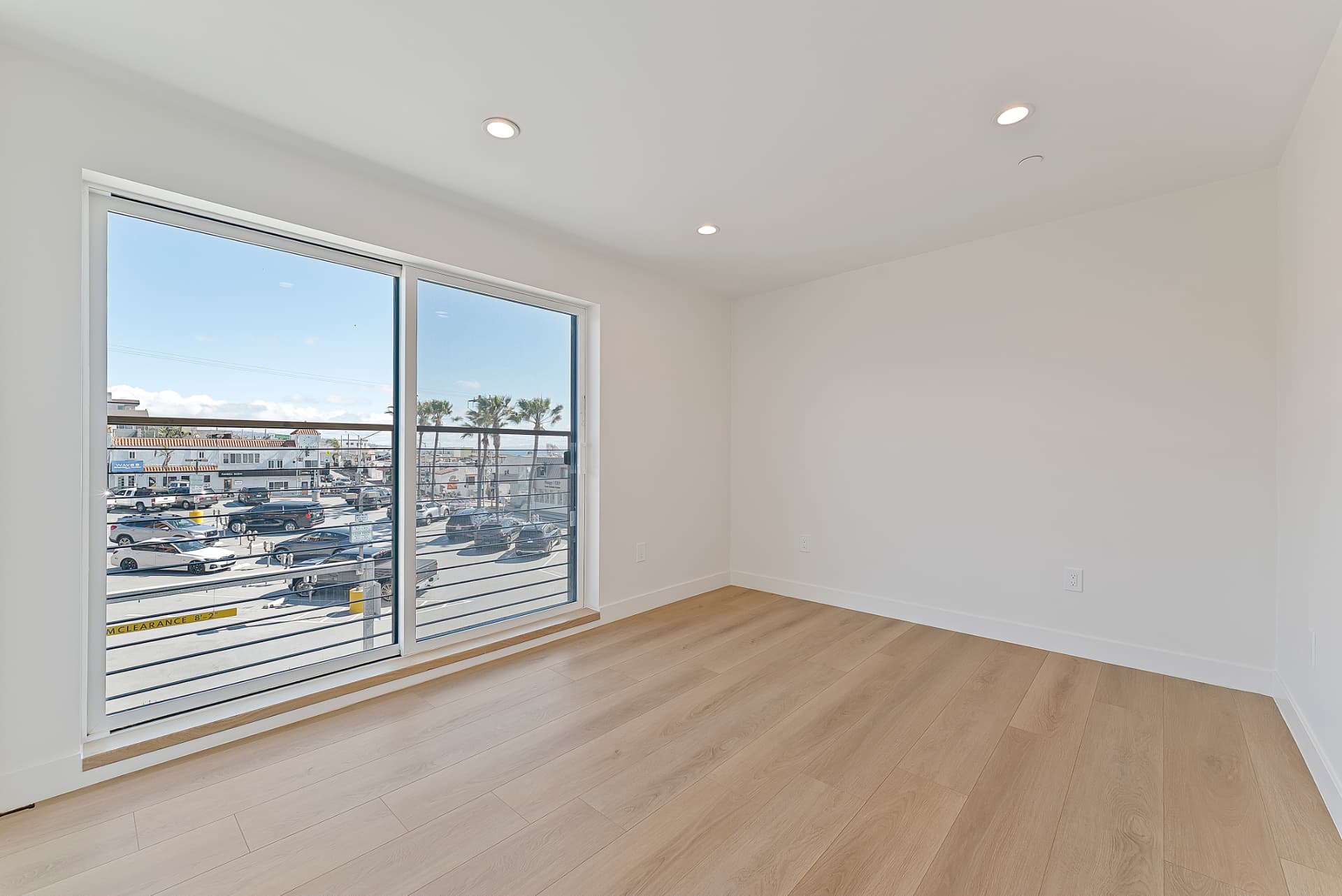 After: Renovated living room with new light wood flooring, fresh paint and sliding glass doors